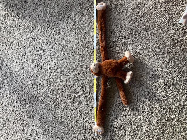 Klettaffe Flexi mit maximal langgezogenem Arm neben Zollstock zur Demonstration der vollen Länge von 90 cmFür Bild 4 (Nelson Grau):